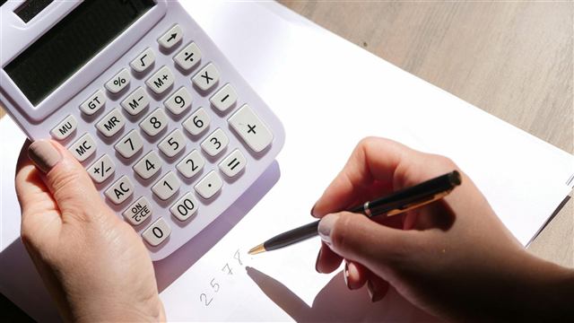 Cálculo manual com calculadora e caneta sobre folha em branco