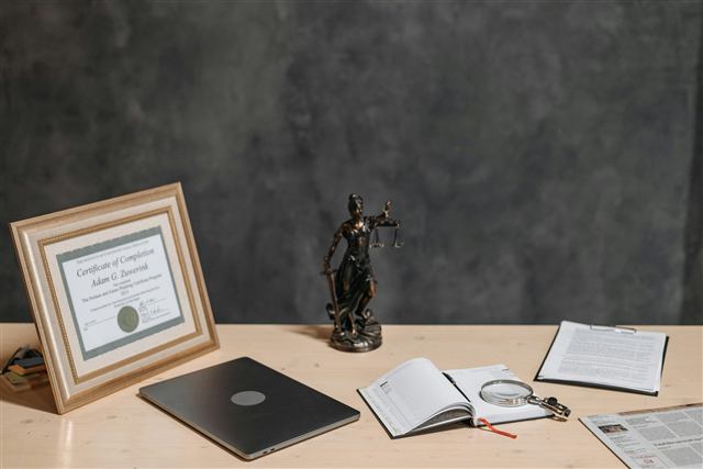 Mesa de trabalho jurídica com notebook, documentos e estátua da justiça